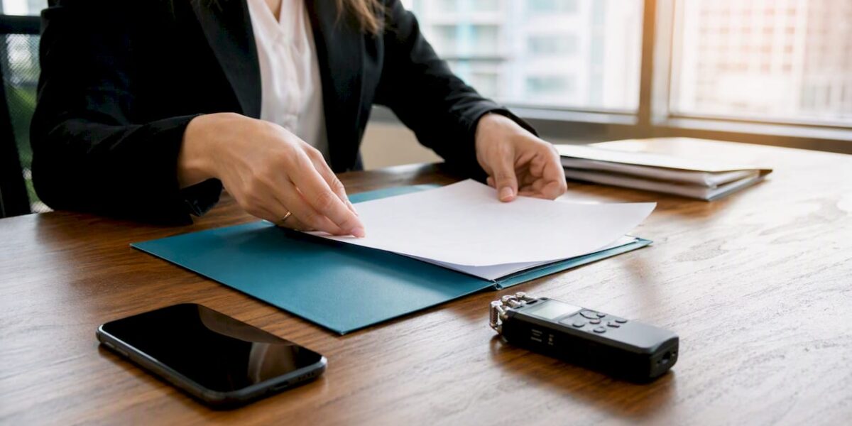 Hands preparing press kit materials on desk