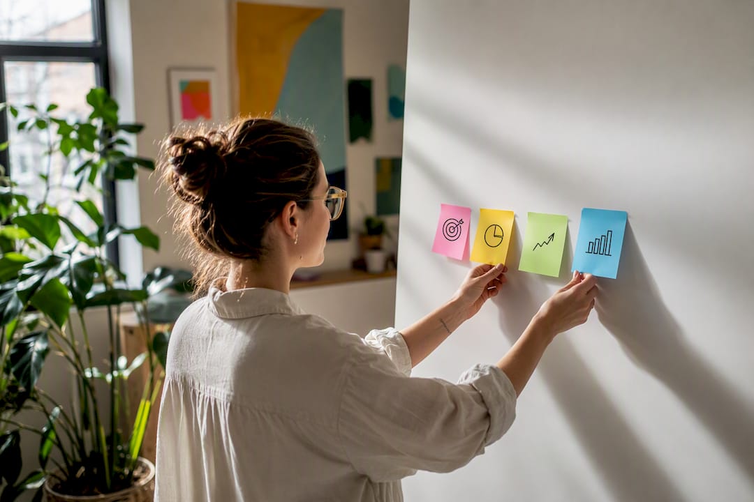 Hands arranging sticky notes for brand metrics
