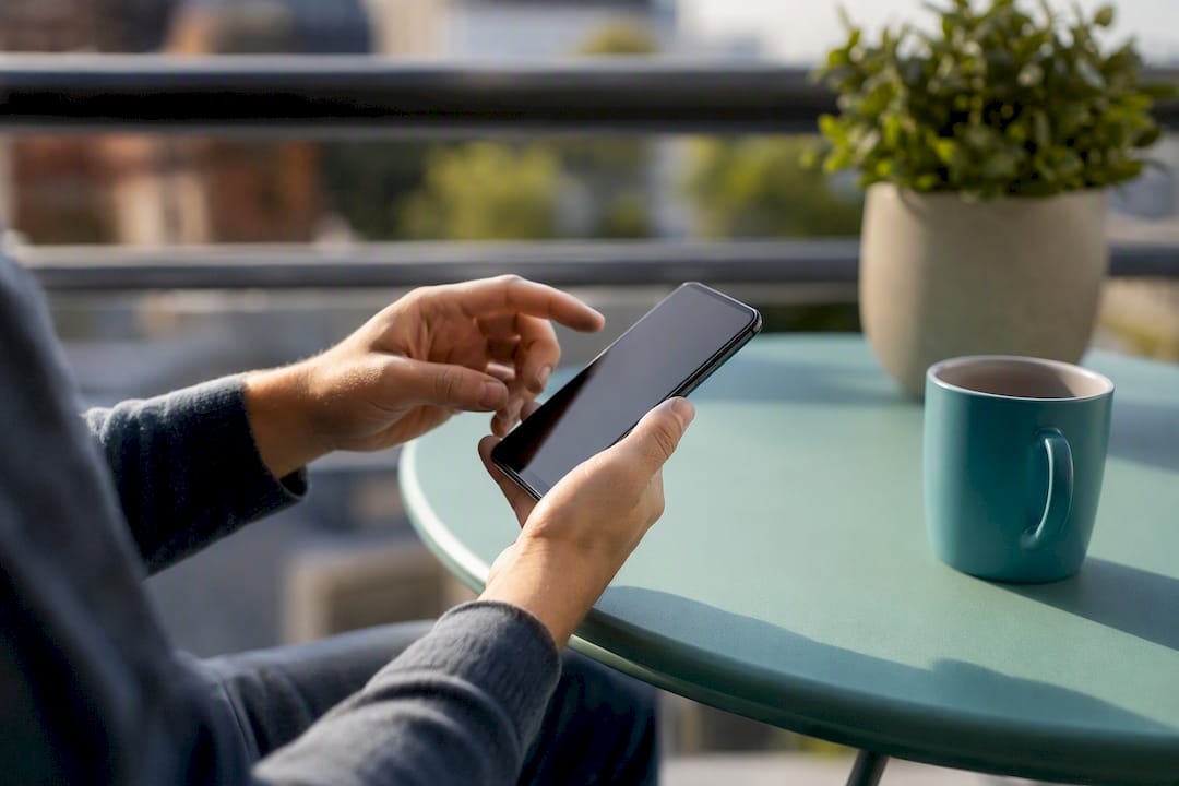 Hands holding smartphone with dark screen cautiously